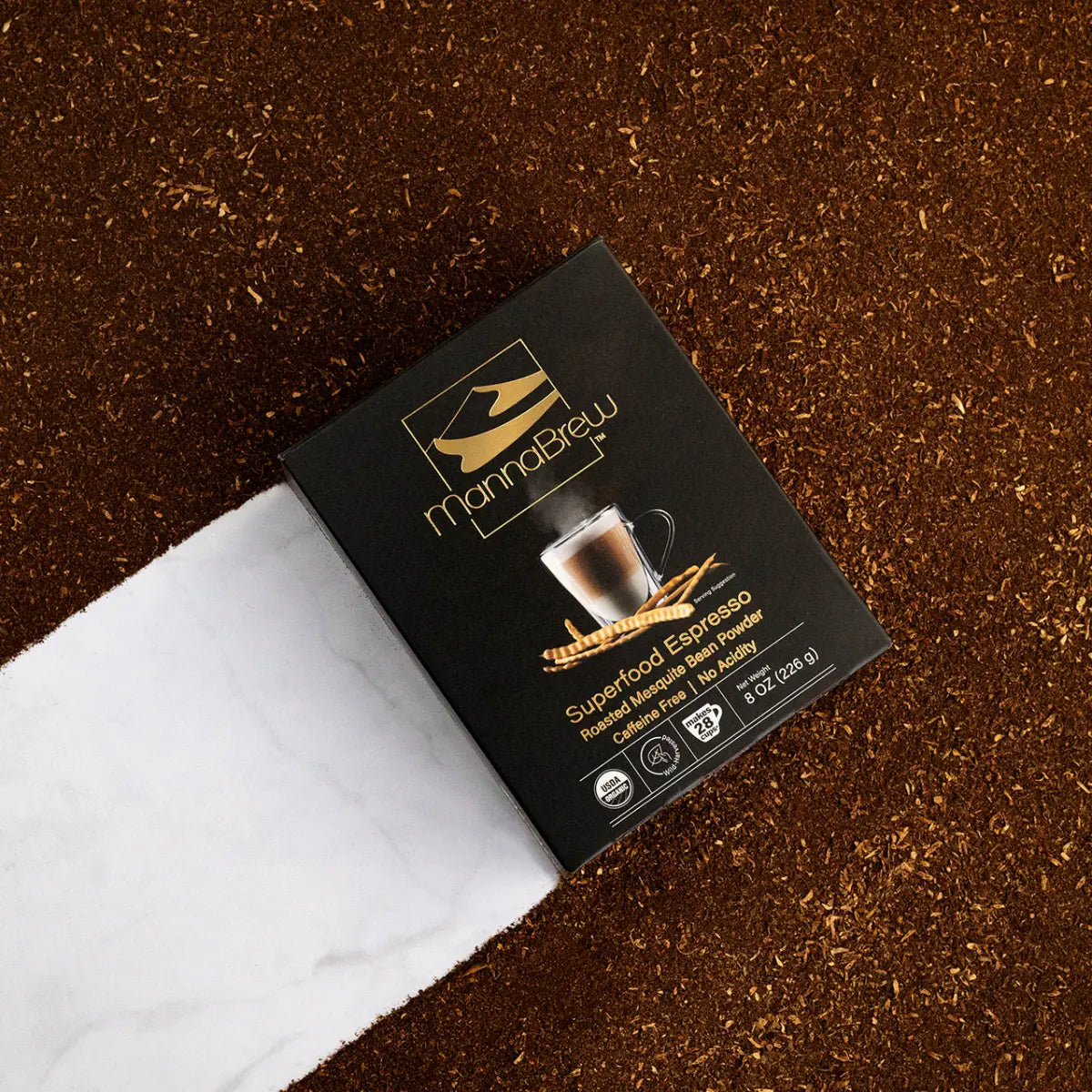 MannaBrew Superfood Espresso packaging on a brown surface with mesquite grounds.