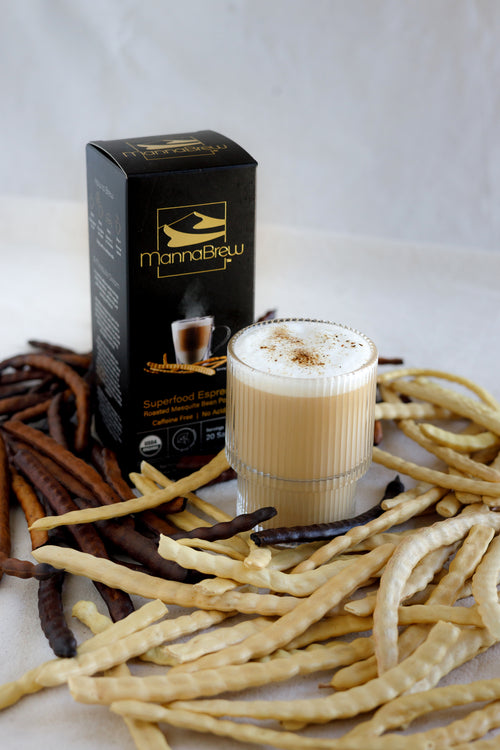 Glass of coffee with MannaBrew packaging and mesquite seed pods on a white background